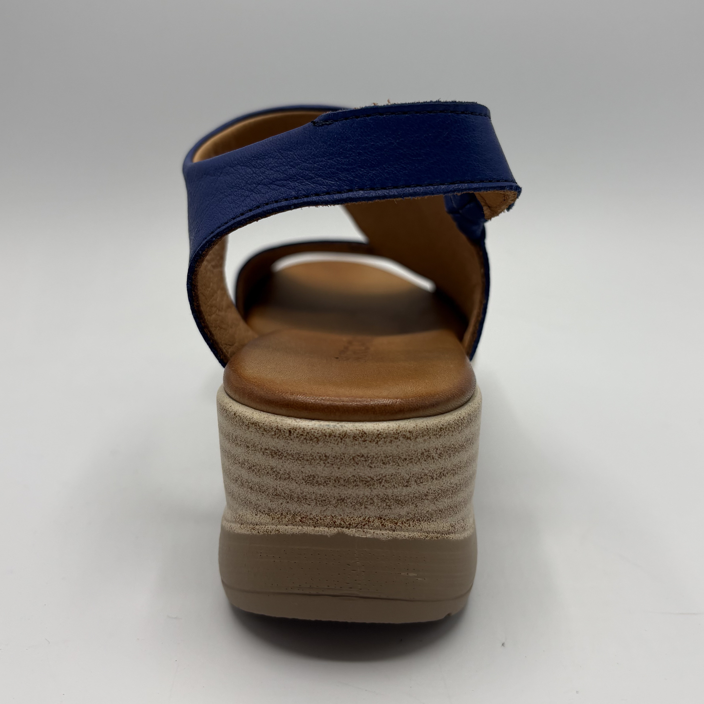 Navy sandal with a brown wedge sole on a white background