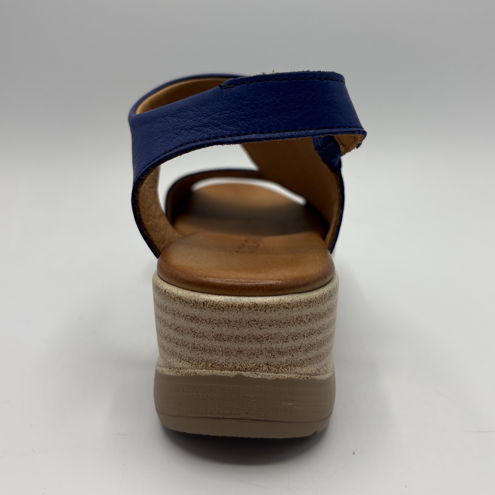 Navy sandal with a brown wedge sole on a white background
