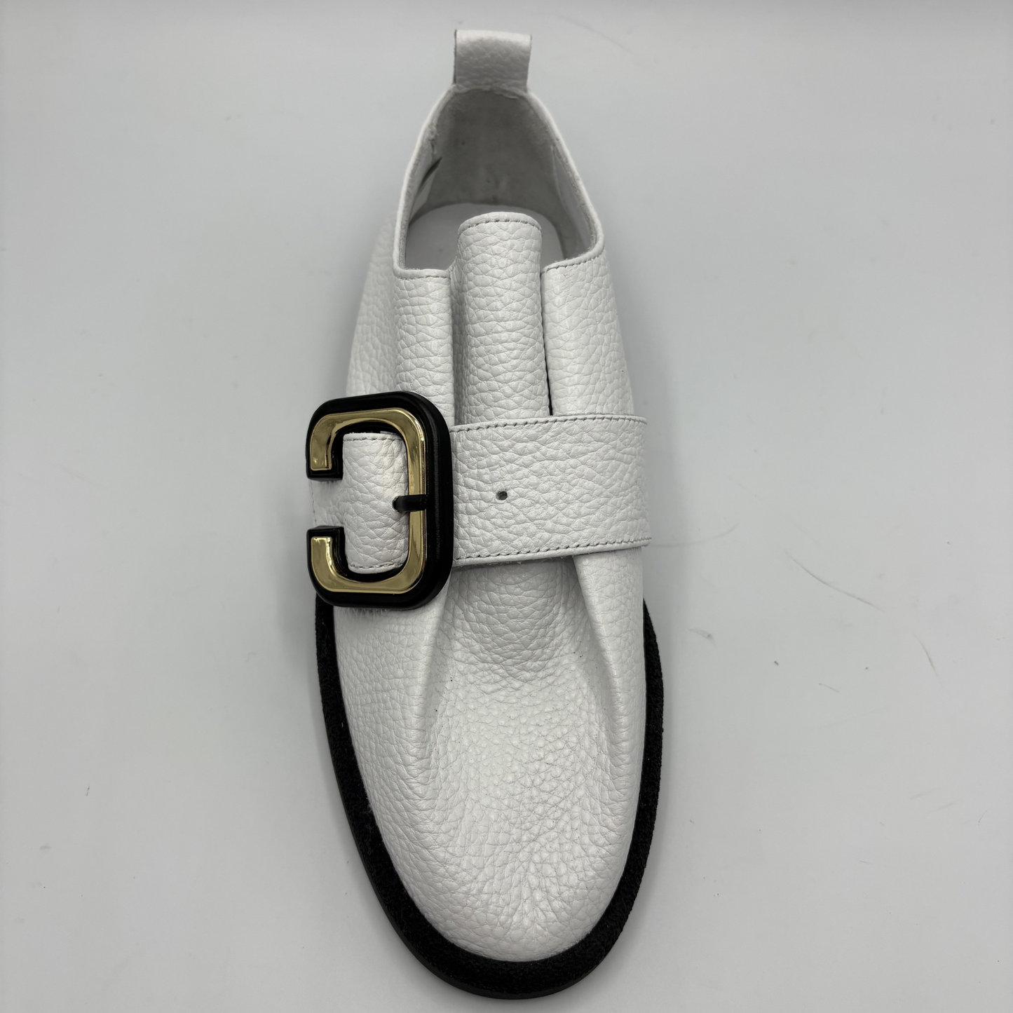 Top  view of a white leather shoe with a gold buckle