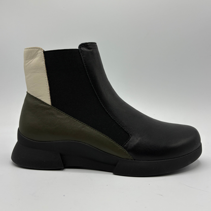 A low-top ankle boot with a black elastic side panel, black leather toe and heel, and an olive green leather side panel, finished with a chunky black sole on a light gray background.
