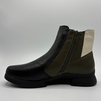 A women's ankle boot in black leather with olive green side panels and a cream-colored inner heel detail, featuring a side zipper, shown against a neutral gray background.