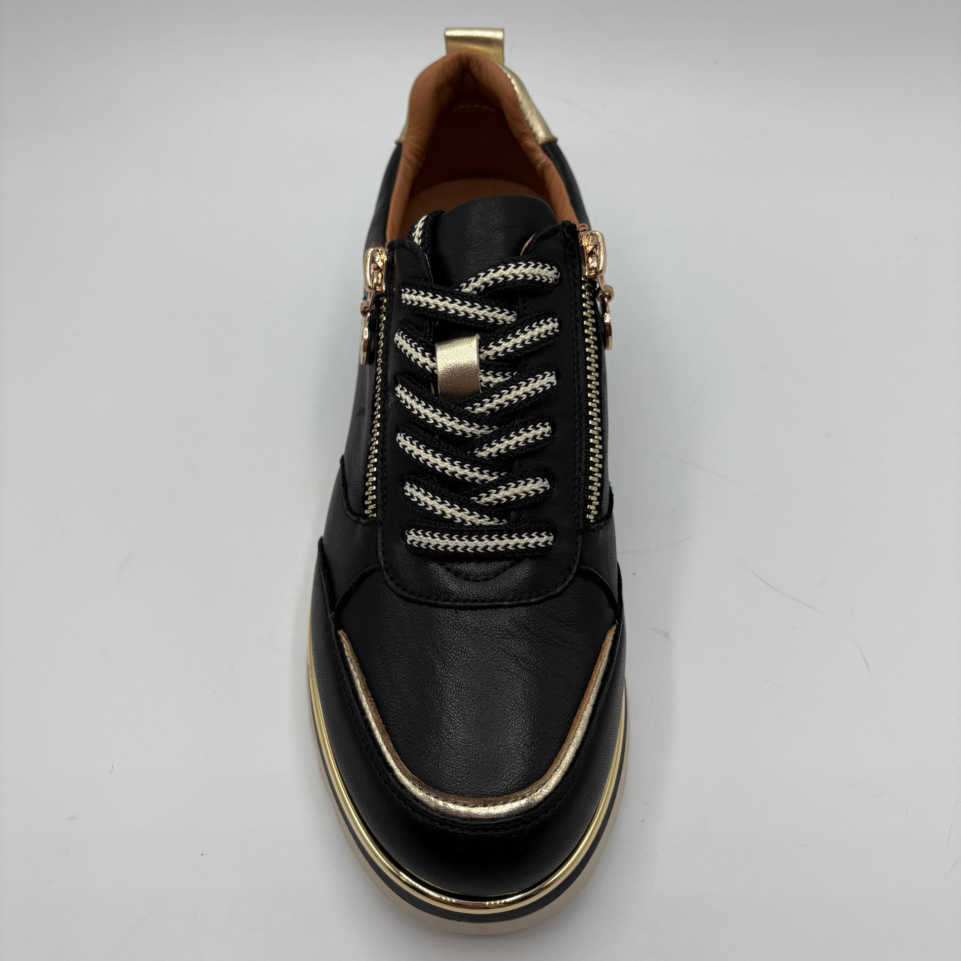 A black leather side-zip sneaker with decorative white and gold braided laces, gold-tone hardware, and a gold trim accent along the toe and sole, shown from a top-down view on a light gray background.