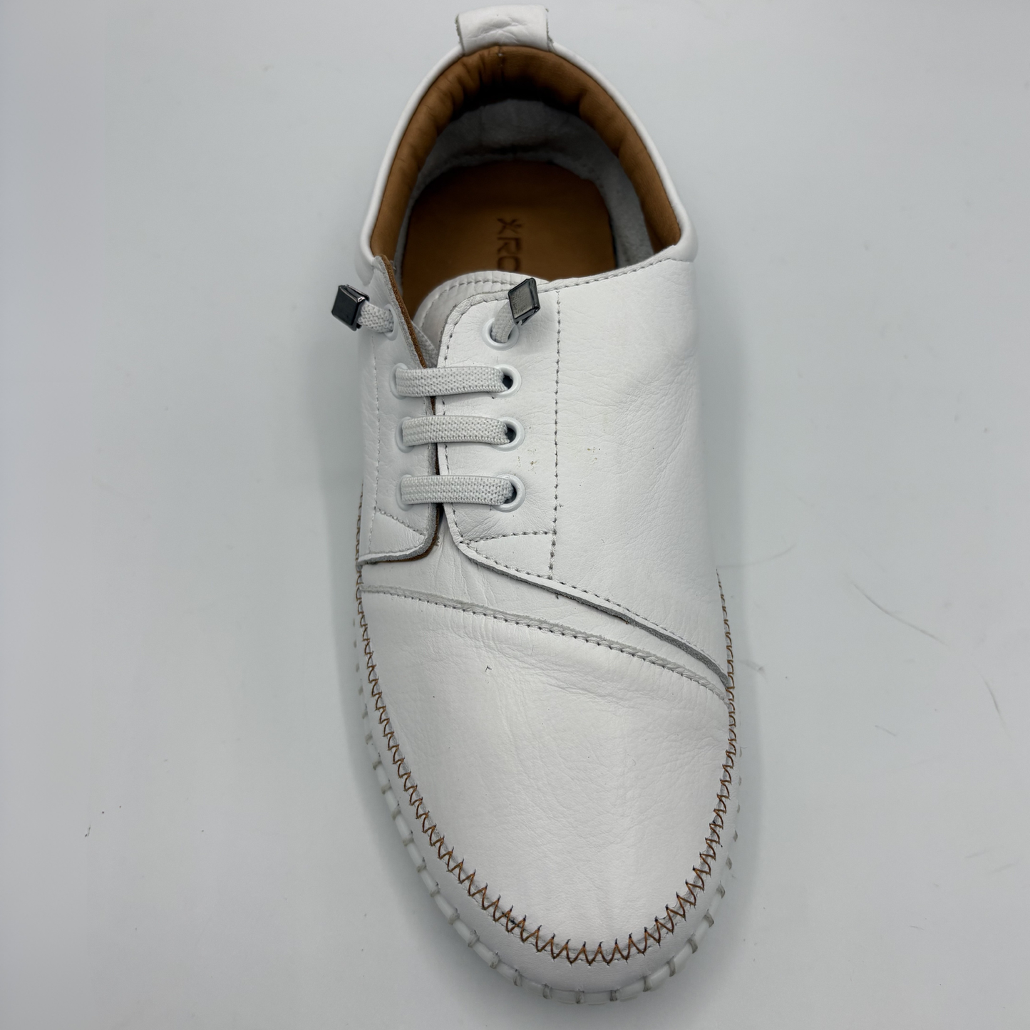 Top view of a white leather shoe with off center laces