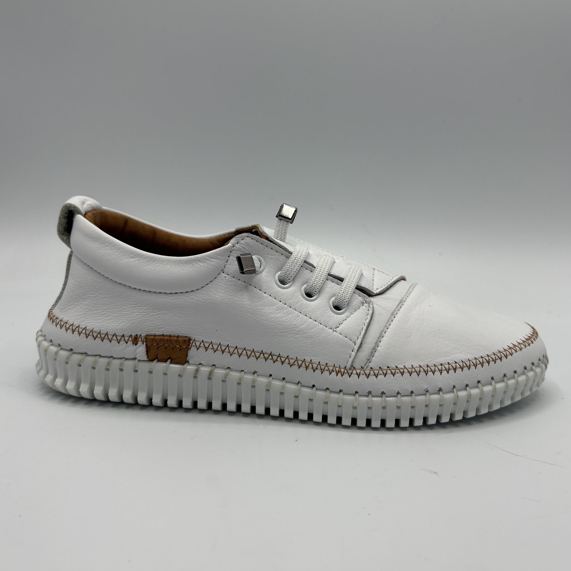 Right facing view of a white leather shoe with off center laces