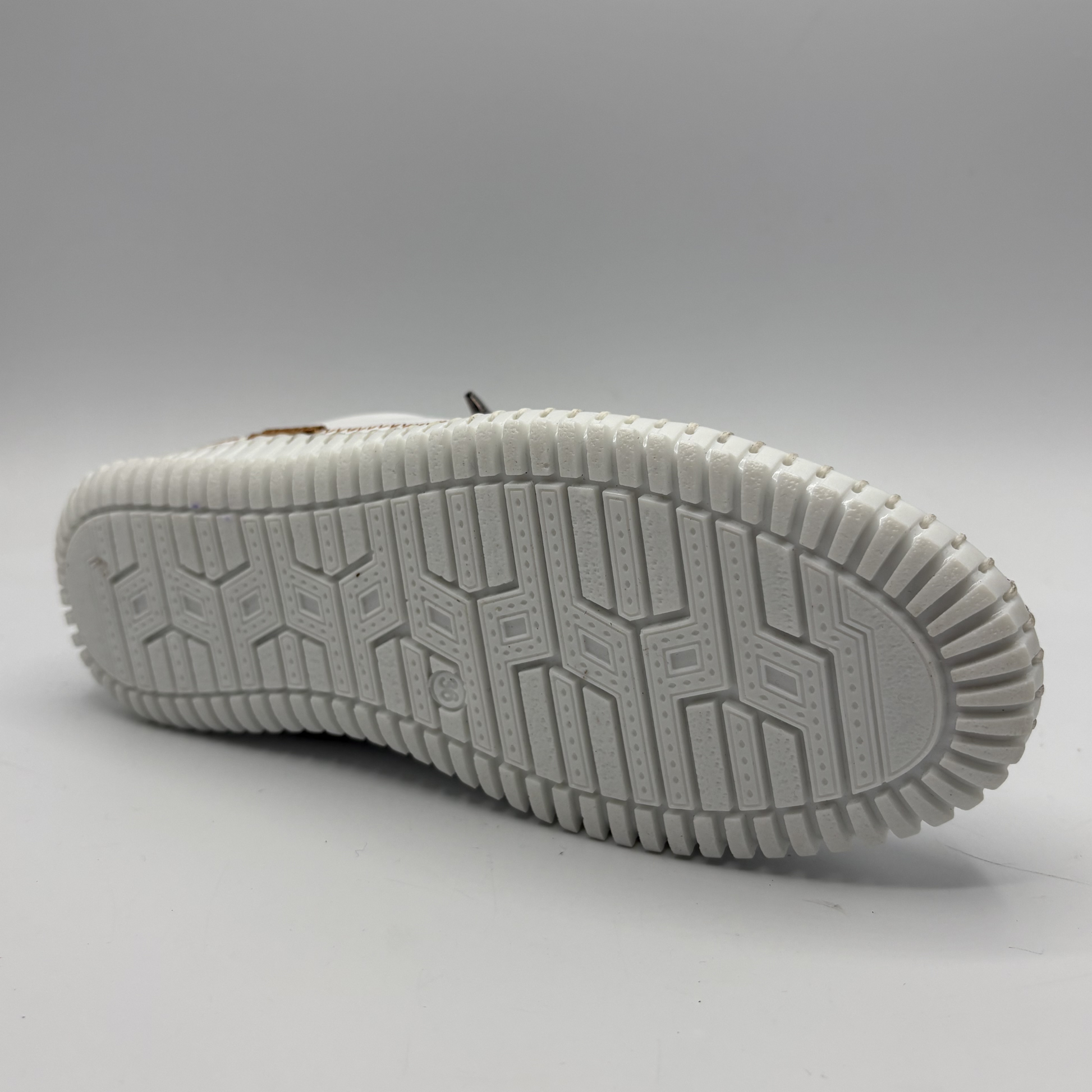 Bottom view of a white leather shoe with off center laces