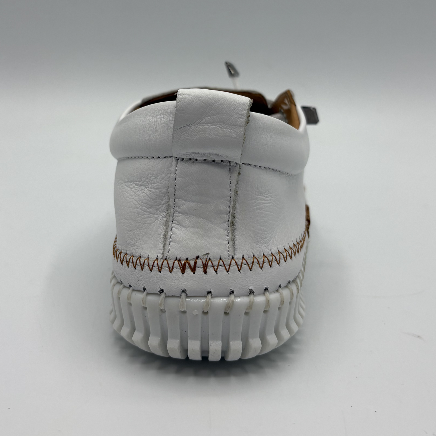 Back view of a white leather shoe with off center laces