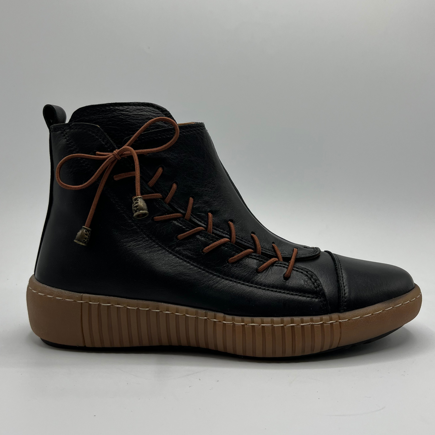 Black ankle boot with brown sole on a gray background