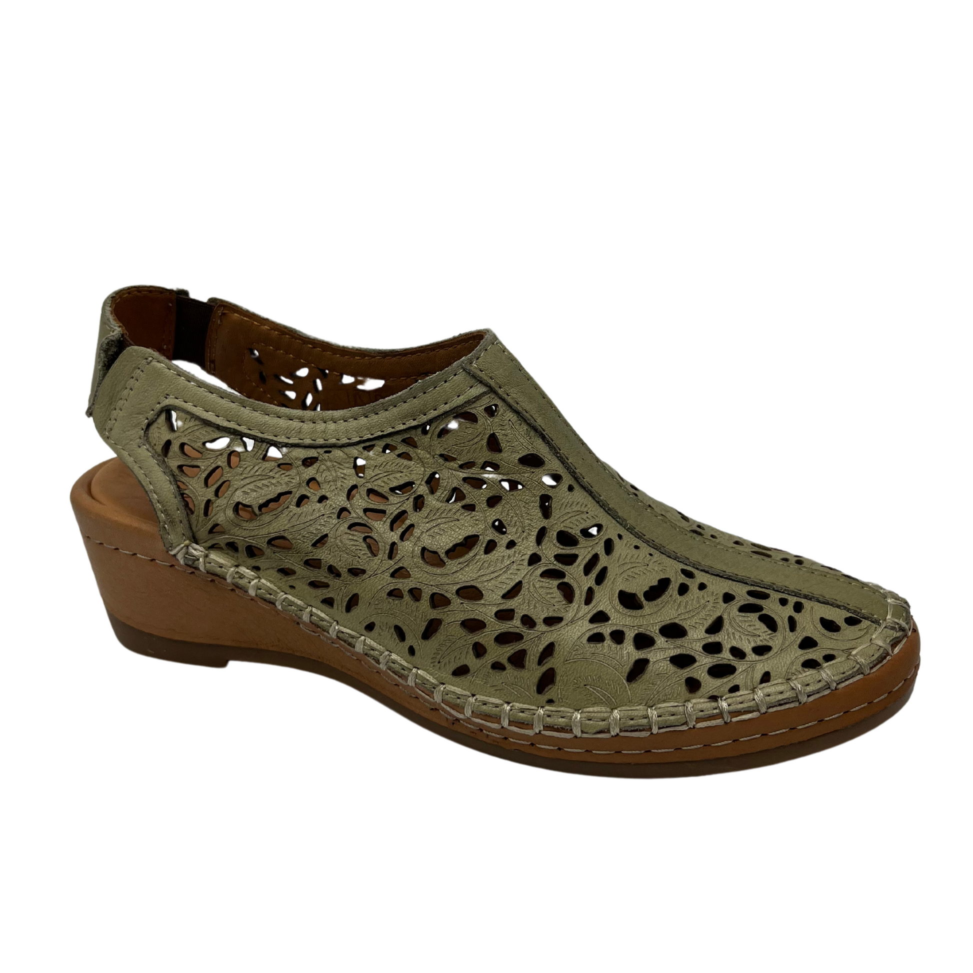 45 degree angled view of light green leather shoe with cut out design with low wedge heel