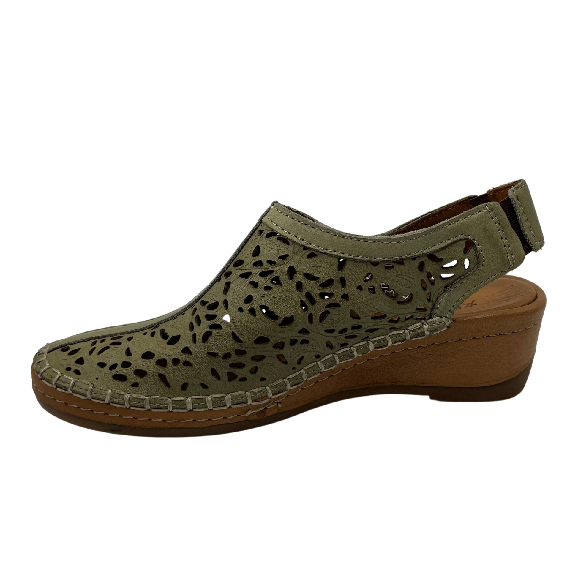 Left facing view of light green leather shoe with cut out design with low wedge heel