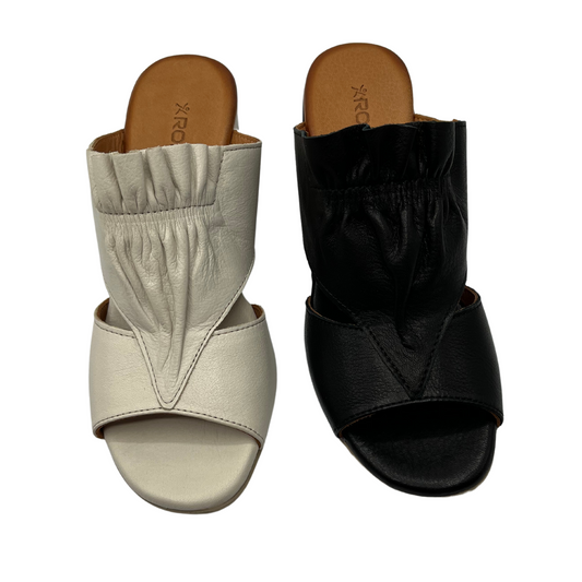Top view of one white leather sandal and one black leather sandal beside each other. Both have a scrunched detail on top and peep toe