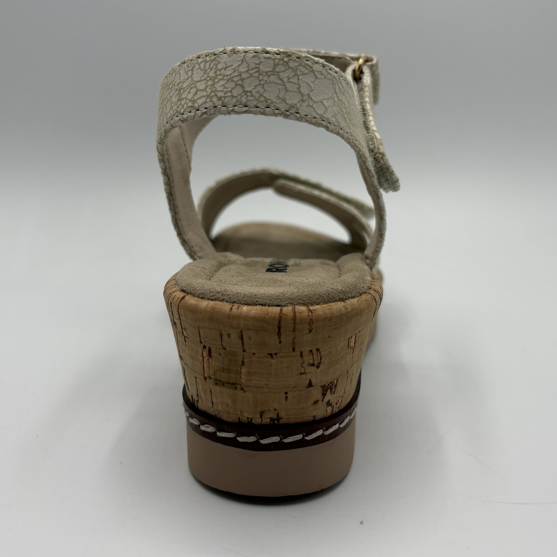 Beige sandal with cork wedge sole on a gray background