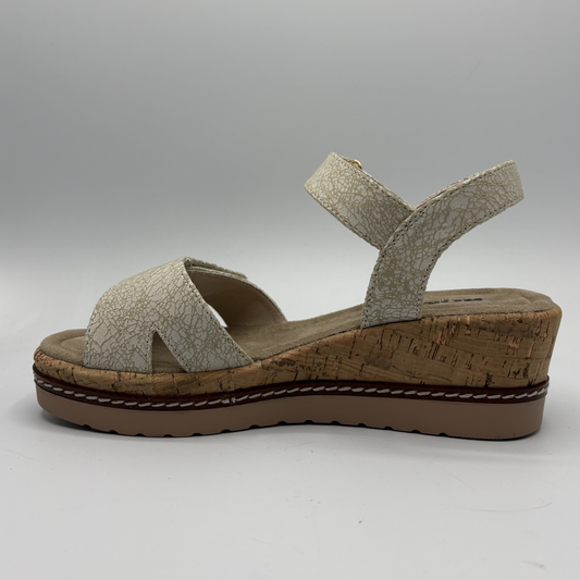 Beige sandal with cork wedge sole on a gray background