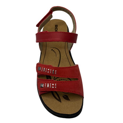 Top view of red leather sandal with silver details on toe straps with black rubber outsole