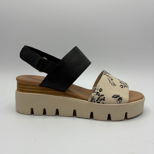 Black strap sandal with floral pattern on a beige platform sole against a gray background