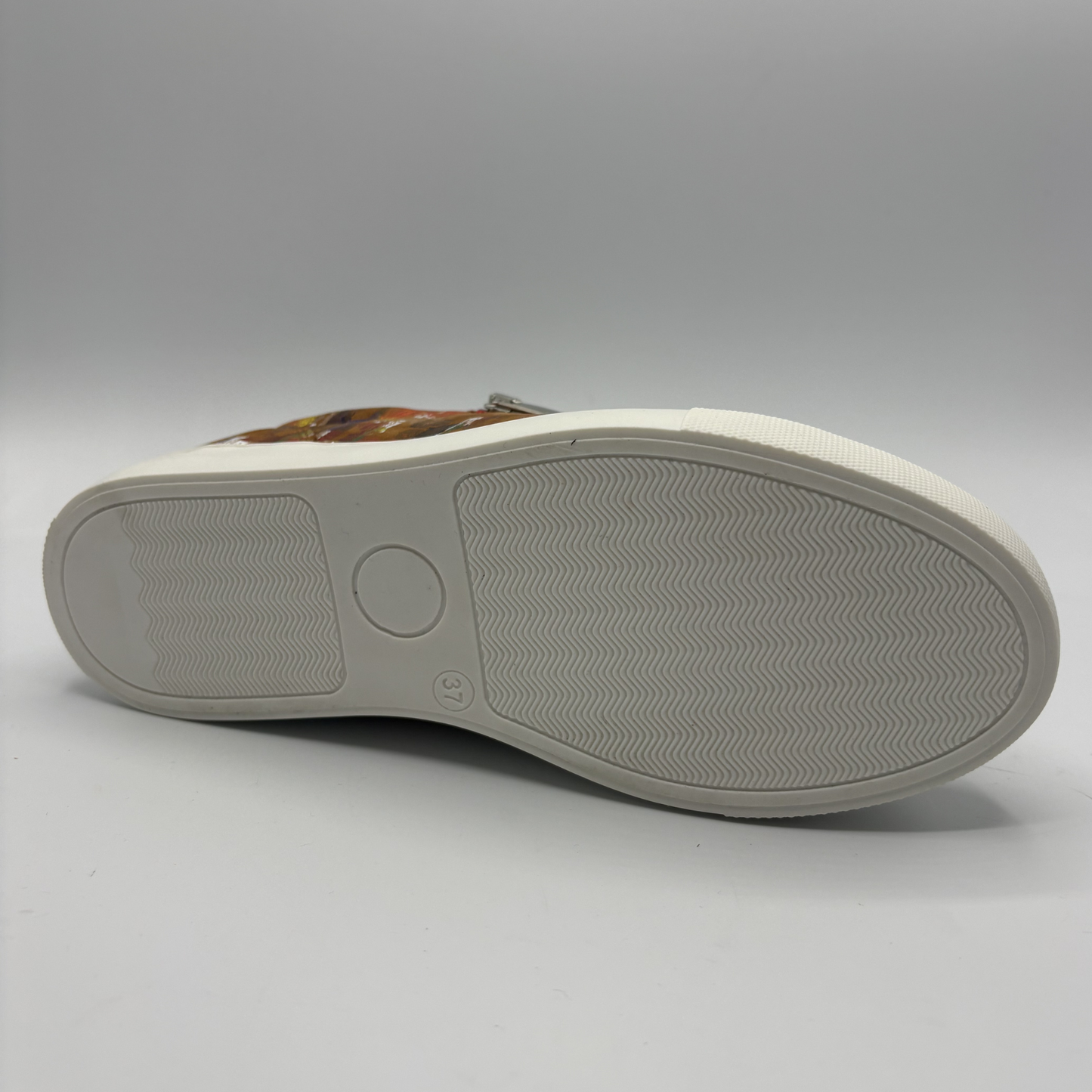 Bottom view of a leather sneaker with a side zip closure and white rubber outsole