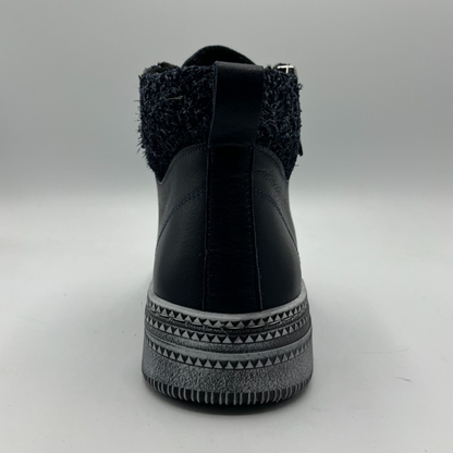 Navy ankle boot with textured top and patterned sole on a gray background