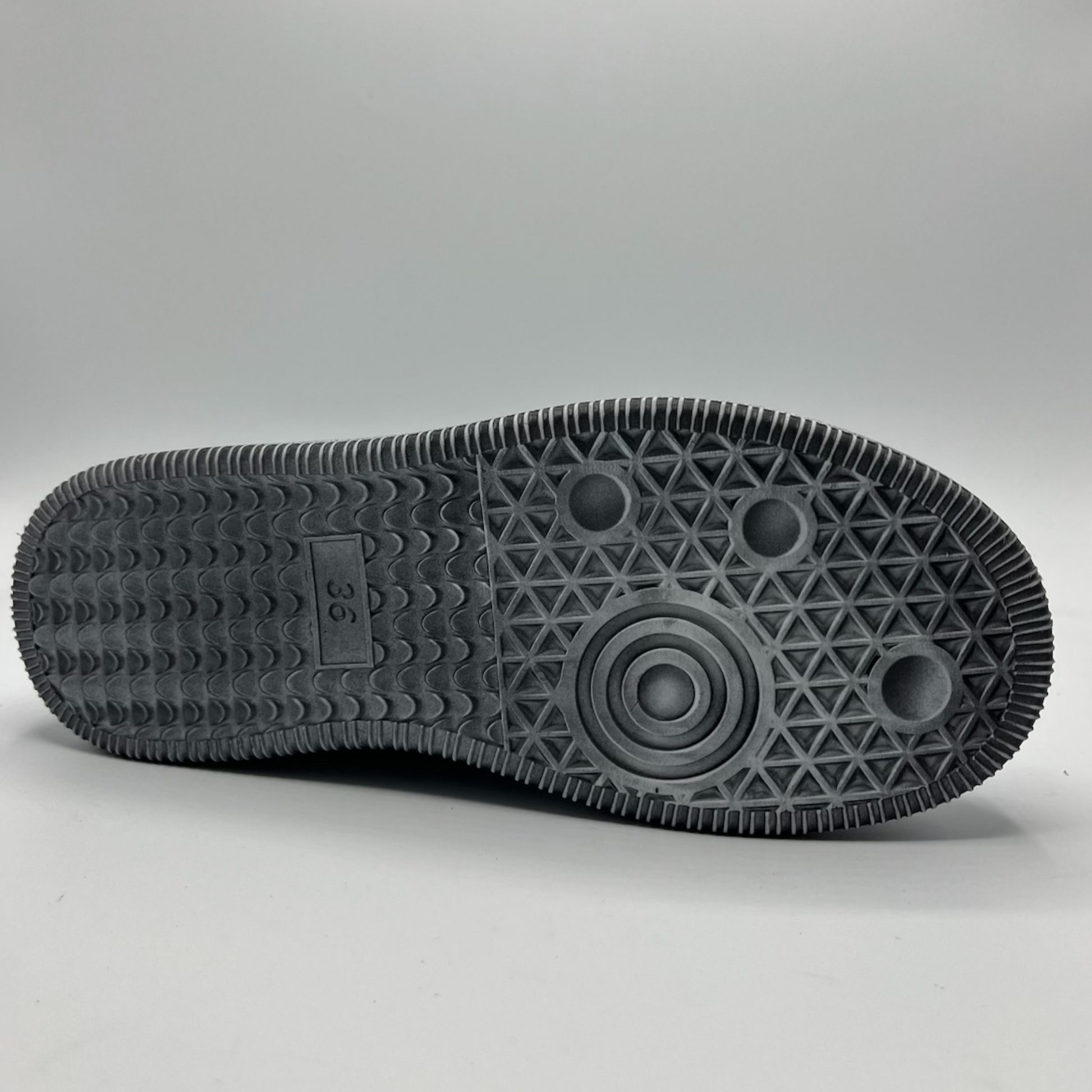 Close-up of a black sole with geometric pattern on a gray background