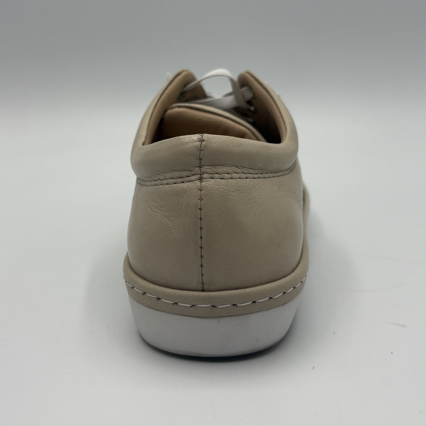 Back view of a beige perforated leather sneaker with a white rubber outsole