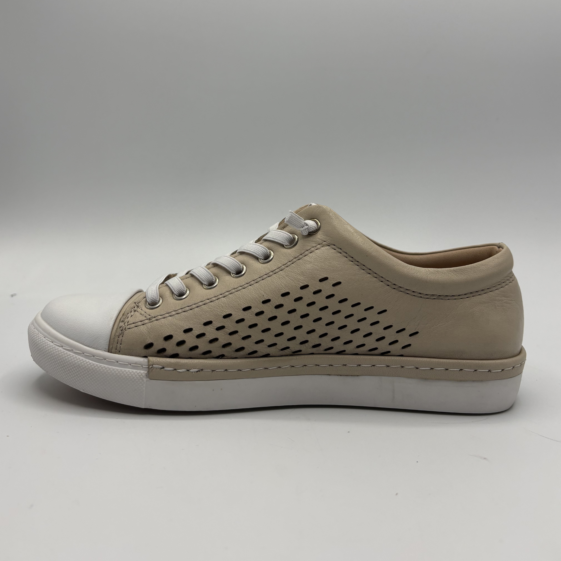 Left facing view of a beige perforated leather sneaker with a white rubber outsole