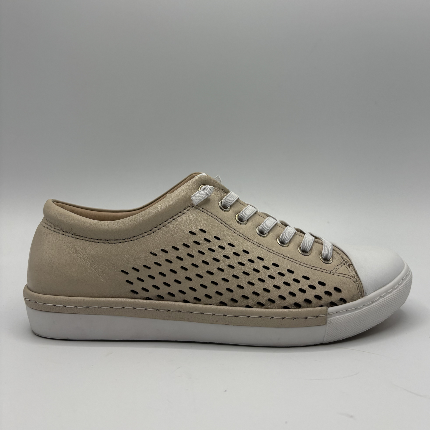 Right facing view of a beige perforated leather sneaker with a white rubber outsole