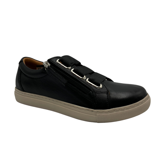 45 degree angled view of black leather sneaker with cream coloured outsole and side zipper closure