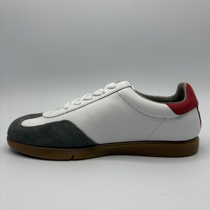 Left facing view of a white sneaker with grey and red accents