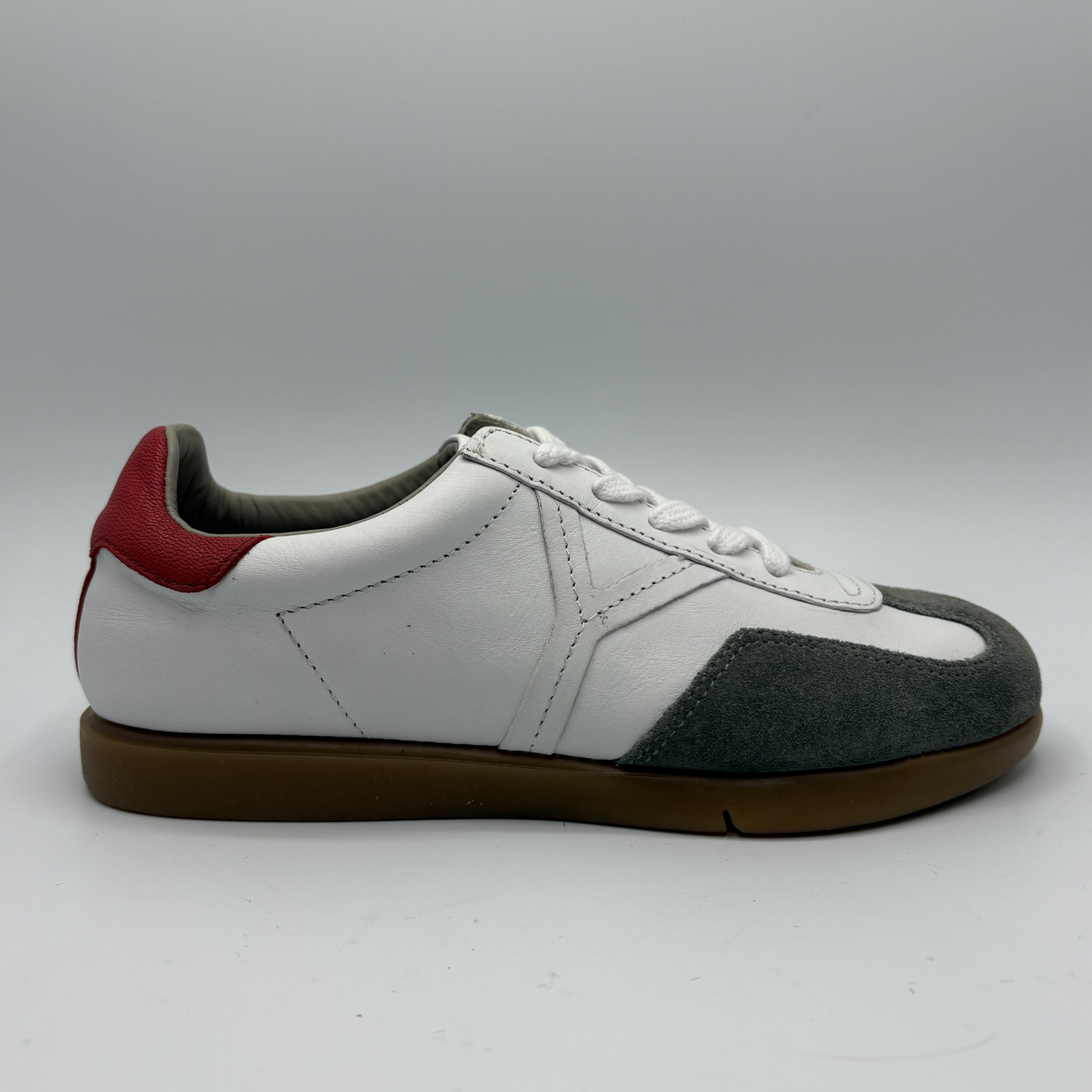 White sneaker with black and red accents on a gray background