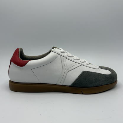 White sneaker with black and red accents on a gray background