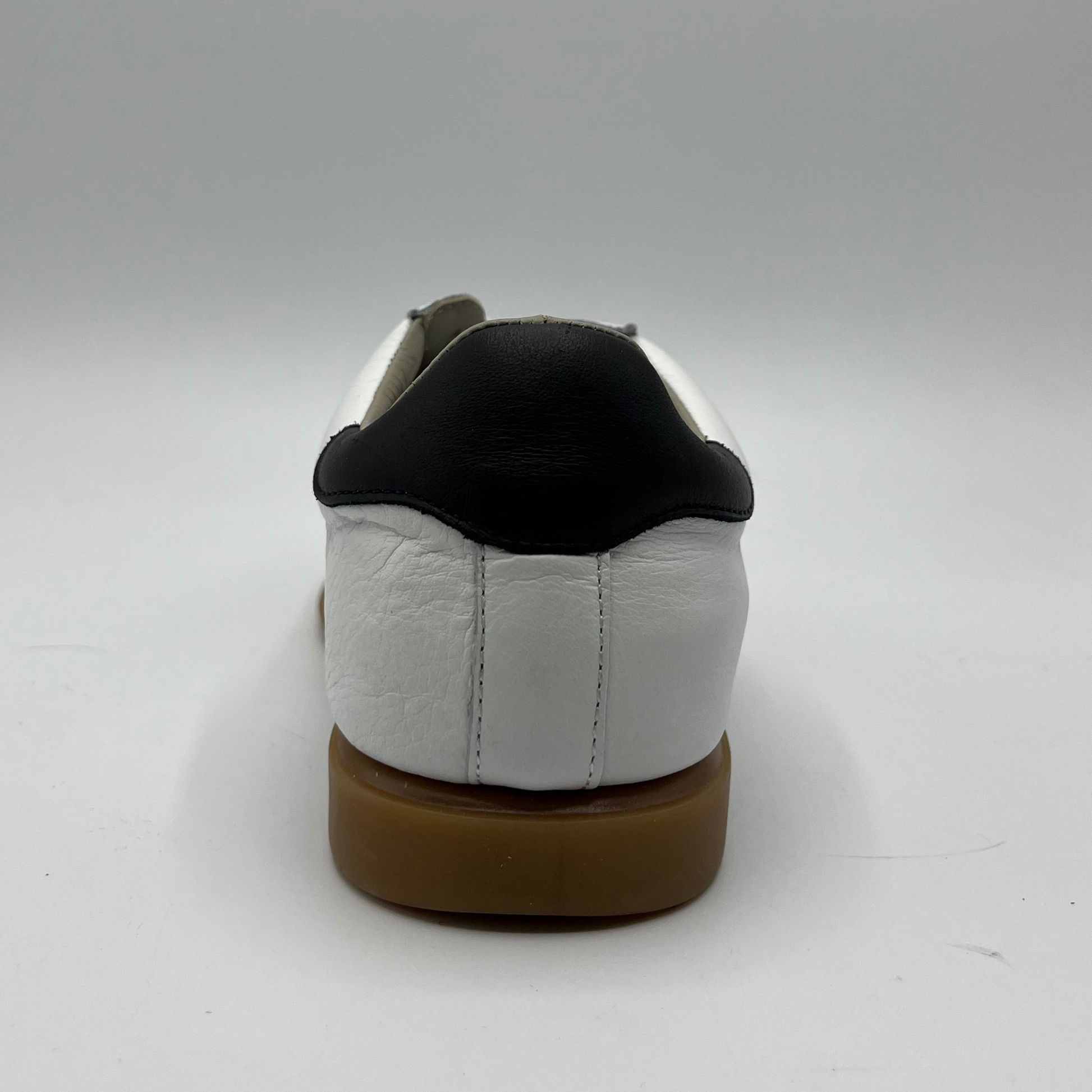 Back view of a leather and suede sneaker with a brown rubber outsole and a padded collar.