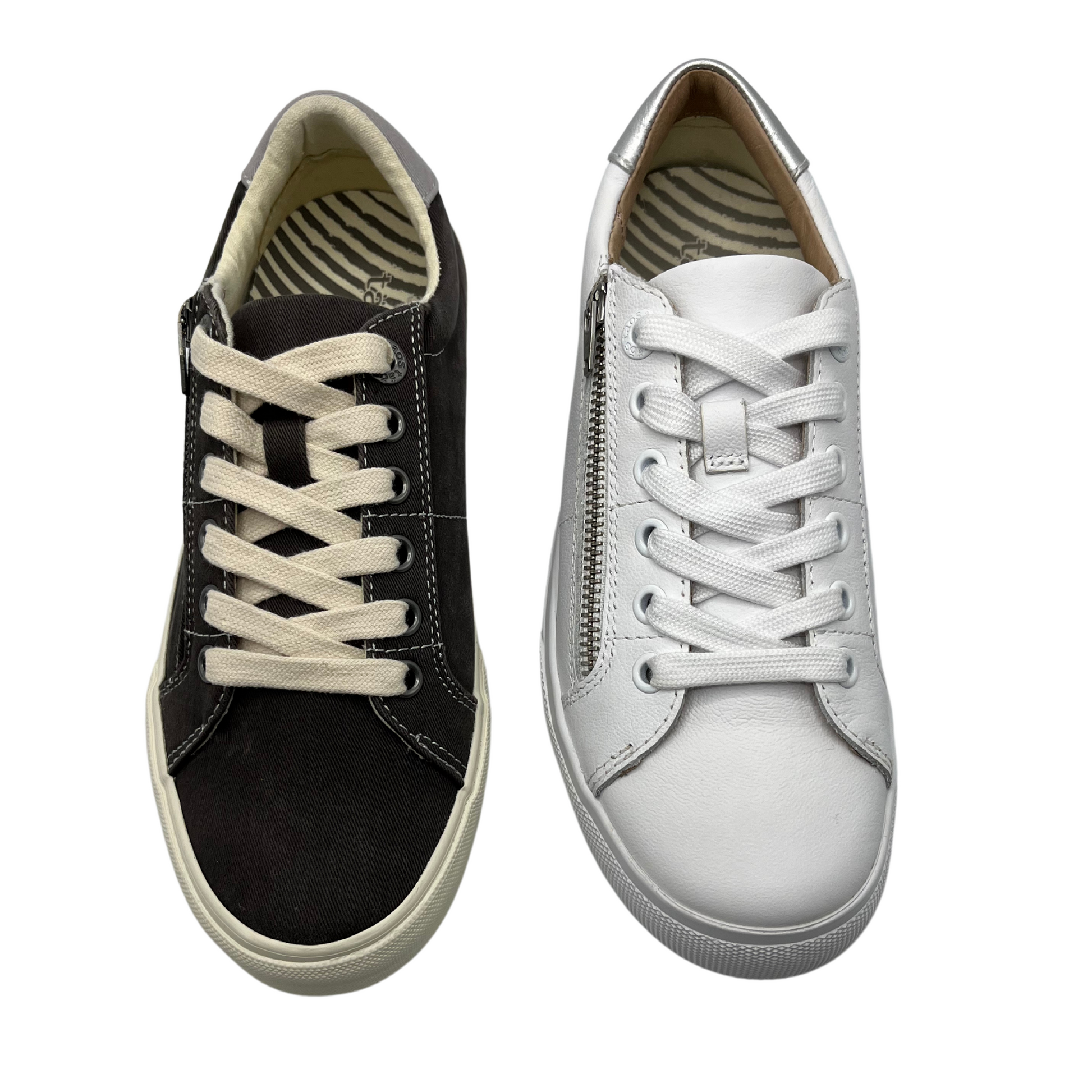 Top view of two sneakers side by side. One is a graphite canvas and the other is white nubuck leather. Both have a side zipper closure and laces up the front