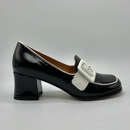 Black shoe with a white buckle on a gray background