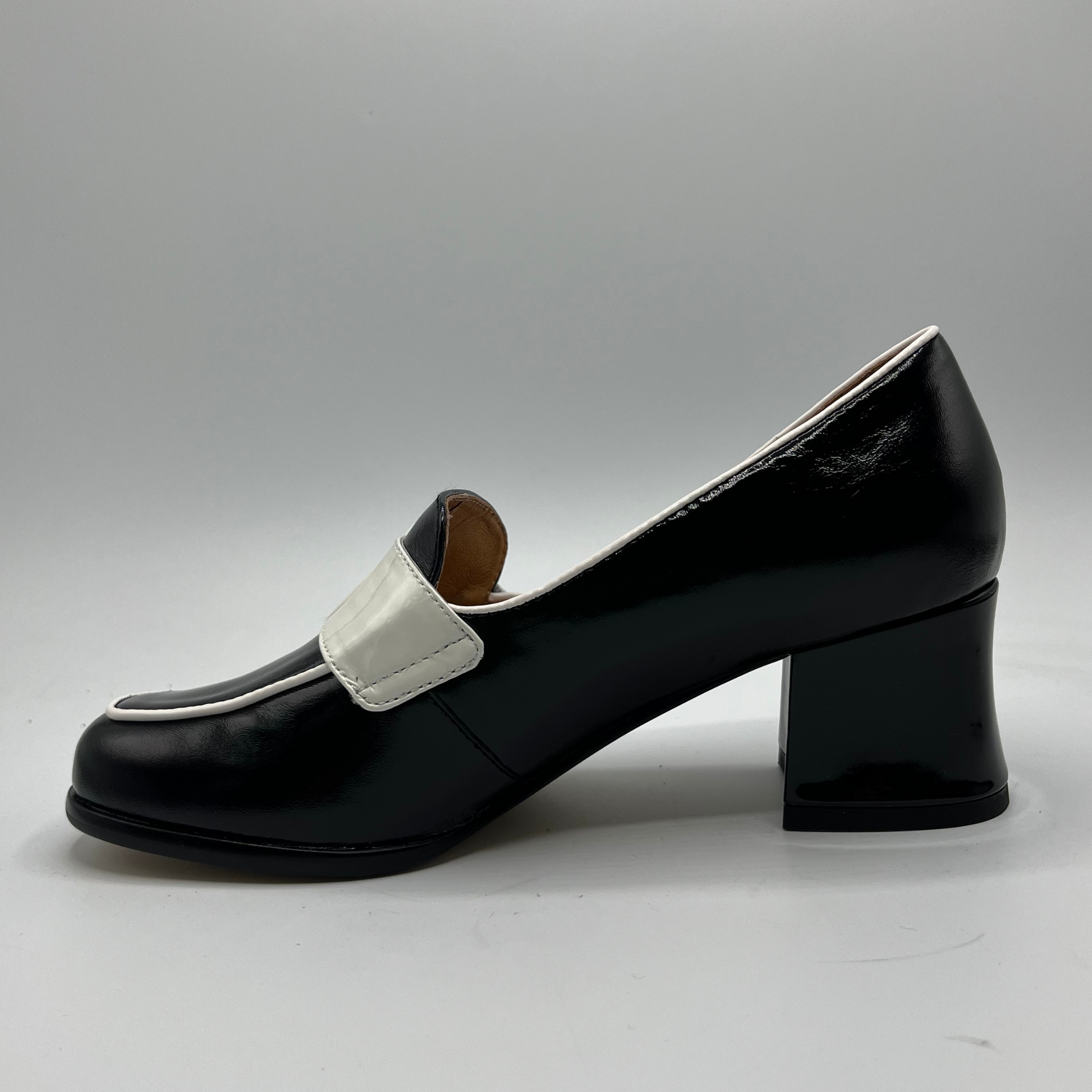 Black shoe with a white strap on a gray background