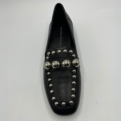 Black loafer shoe with silver studs on a light gray background