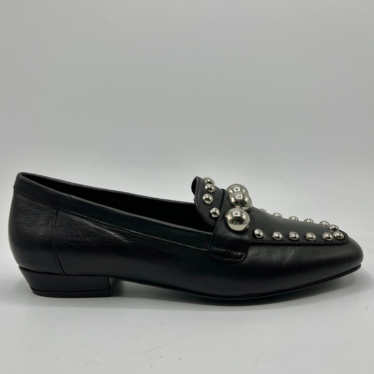 Black loafer shoe with silver embellishments on a gray background