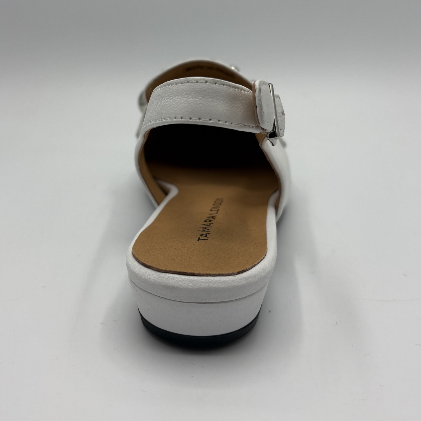 White sandal with a brown insole on a light gray background