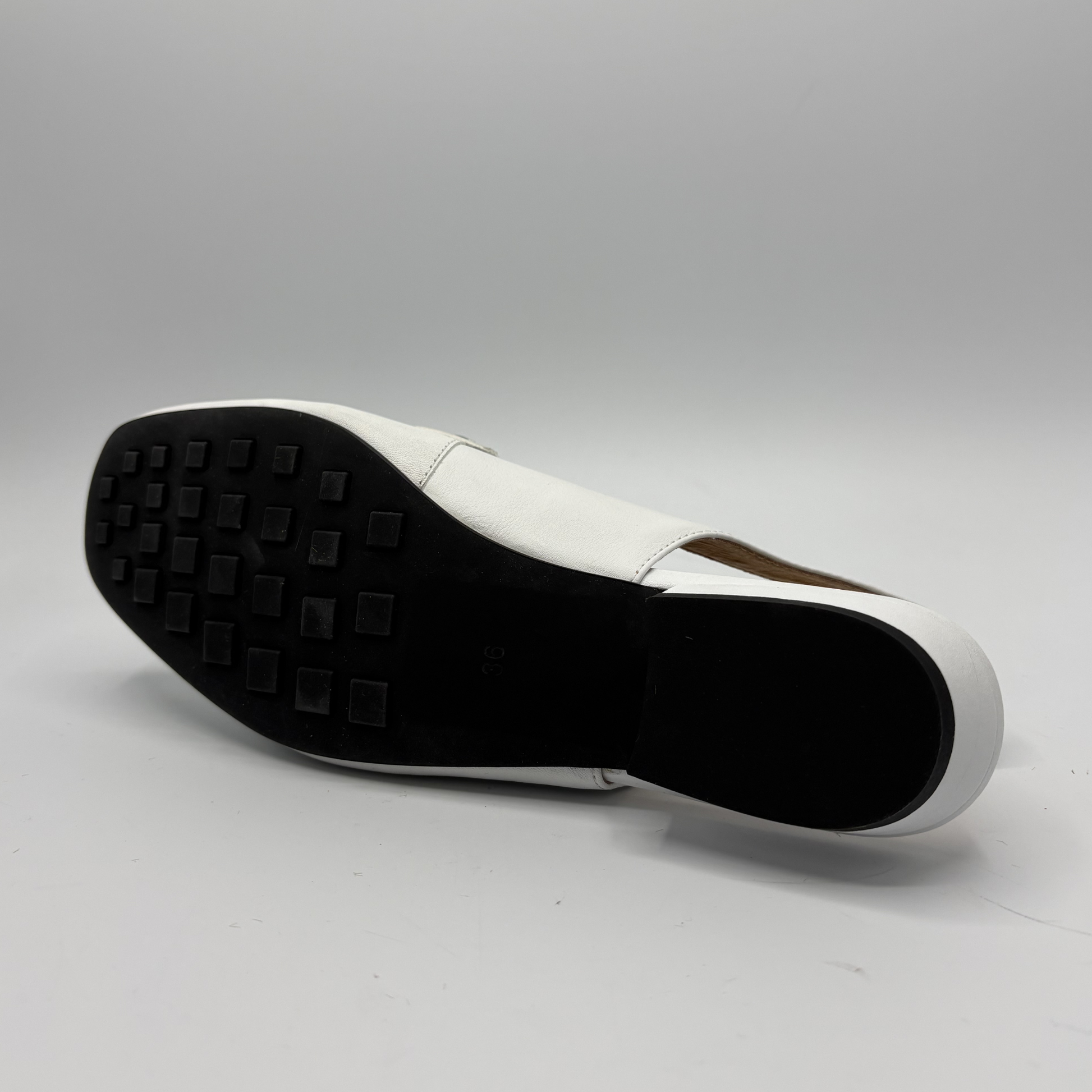 White shoe sole with black tread pattern on a gray background