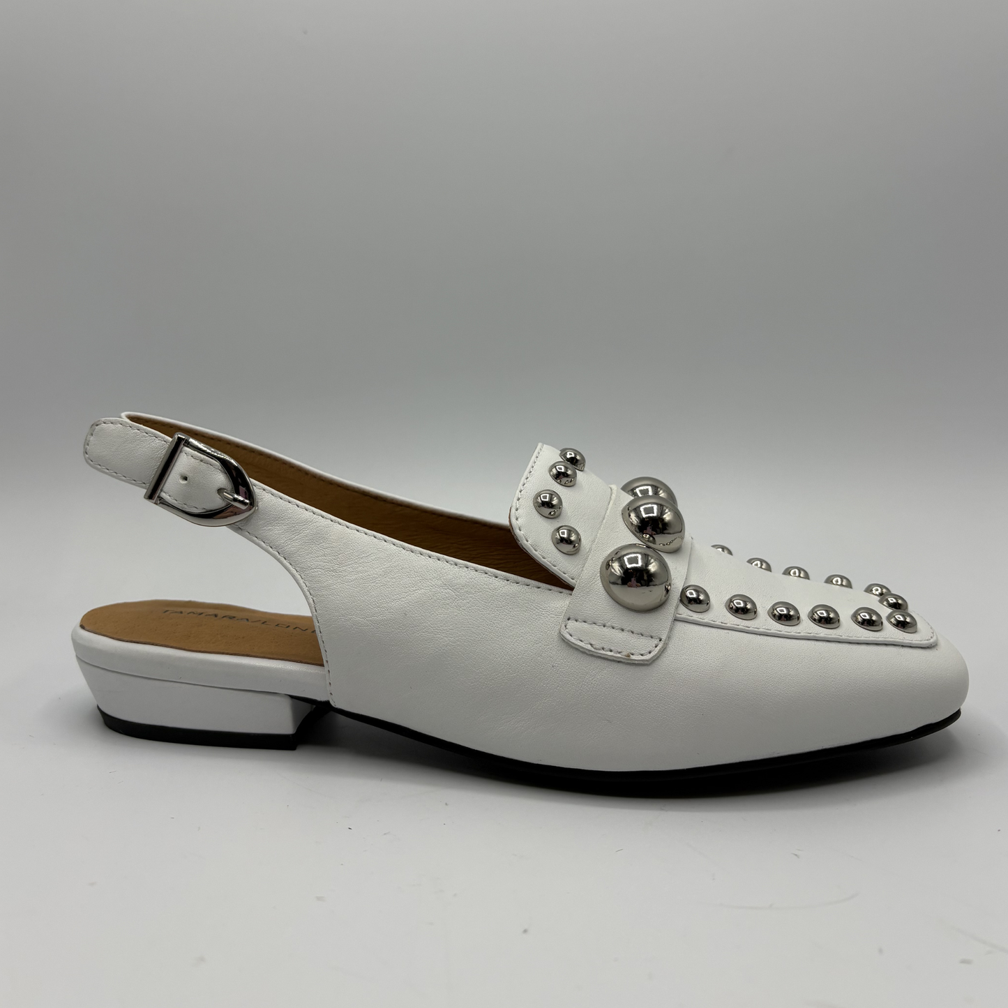 White shoe with silver embellishments on a gray background