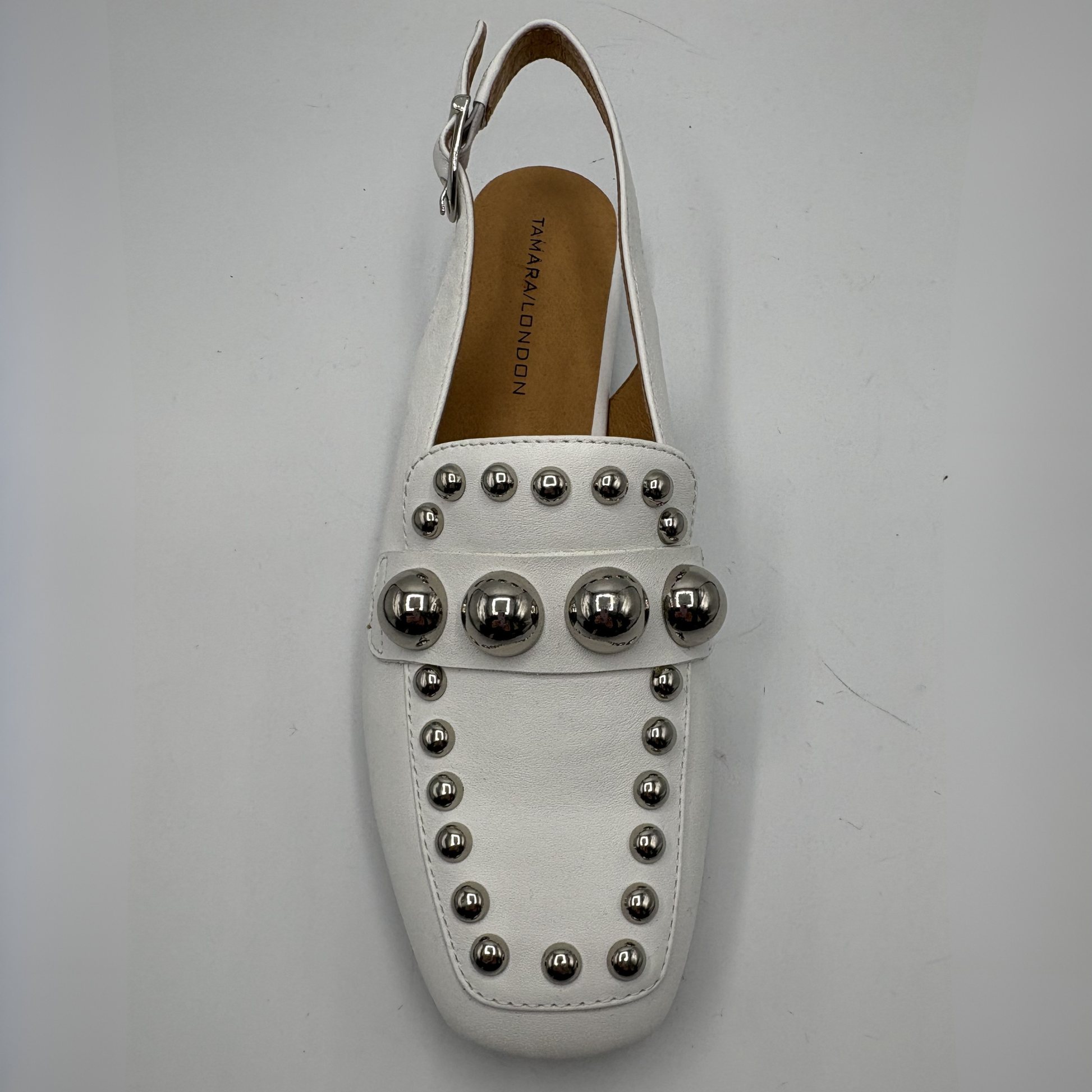 White loafer with silver studs on a light gray background
