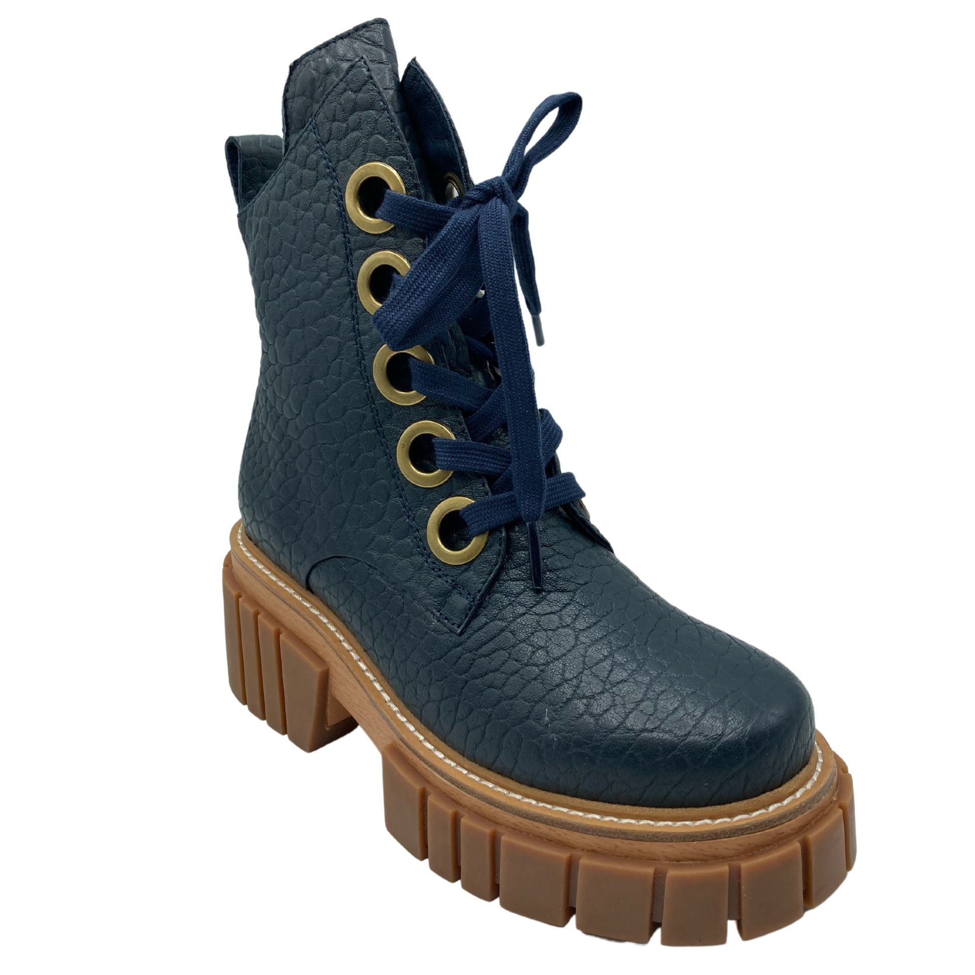 45 degree angled view of navy textured leather boot with gold eyelets, navy laces and brown rubber outsole
