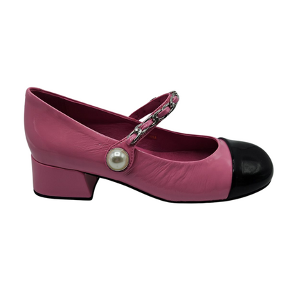 Right facing view of pink and black patent leather mary jane with pearl and chain details on the strap and short block heel