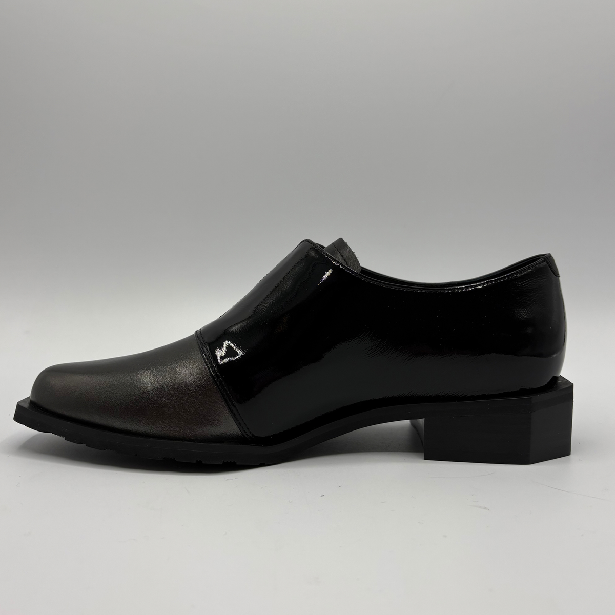 Left facing view of a black shoe with a geometric heel