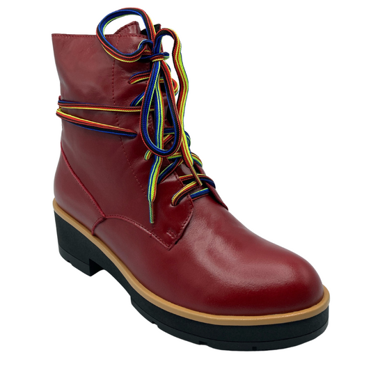 45 degree angled view of red leather short boot with rainbow laces and black rubber outsole