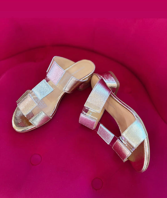 Gold sandals with clear straps on a red background