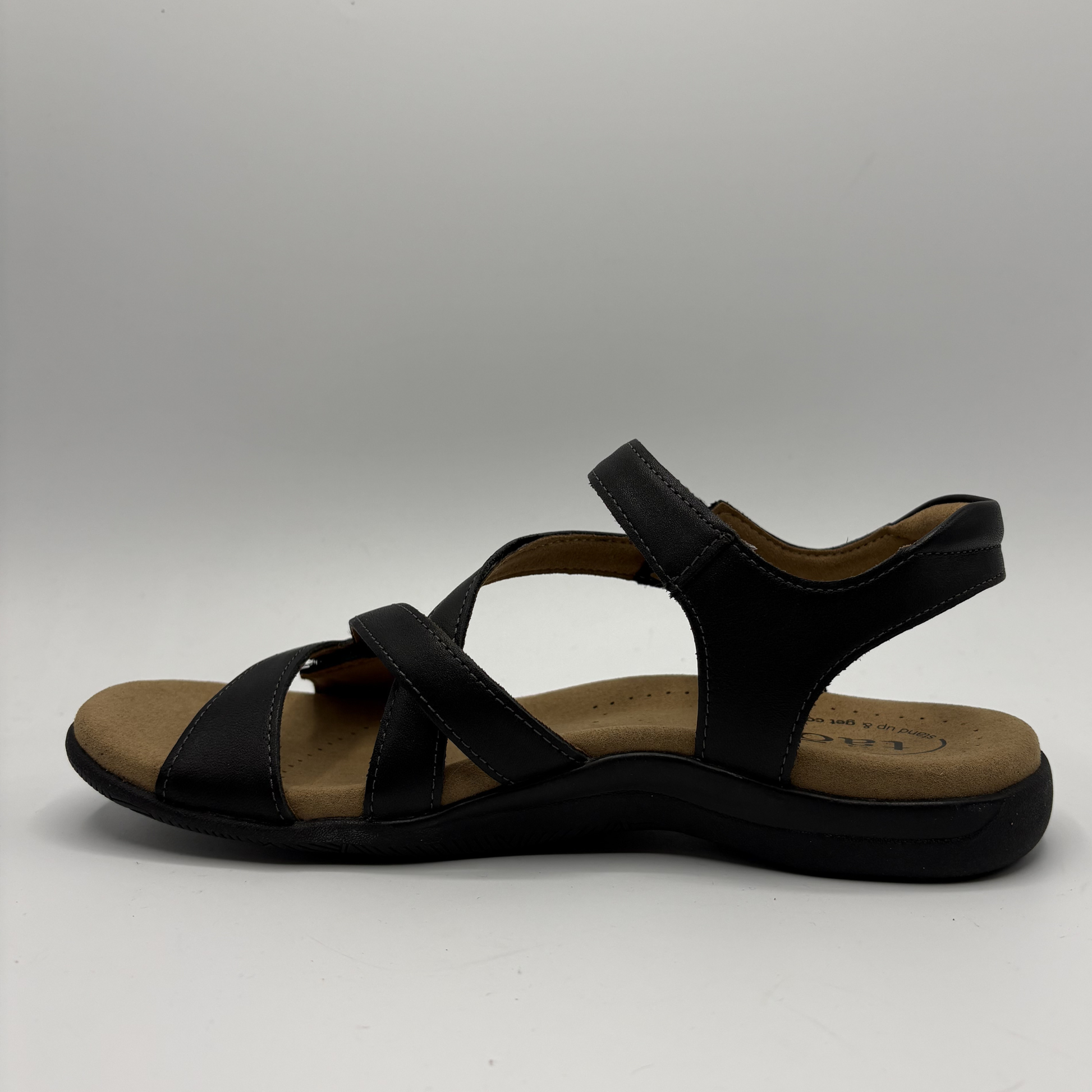 Black sandal with a tan insole on a white background