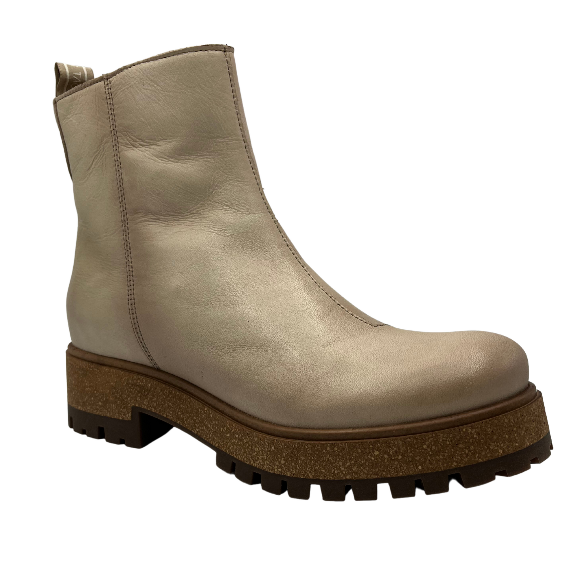 45 degree angled view of ivory leather short boot with rubber and cork outsole with inner zipper closure and pull on tab