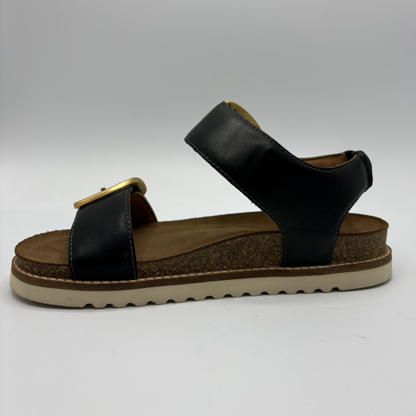 Left facing view of a black strapped sandal with gold buckles and a cork footbed