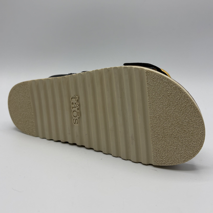 Bottom view of a black strapped sandal with gold buckles and a cork footbed