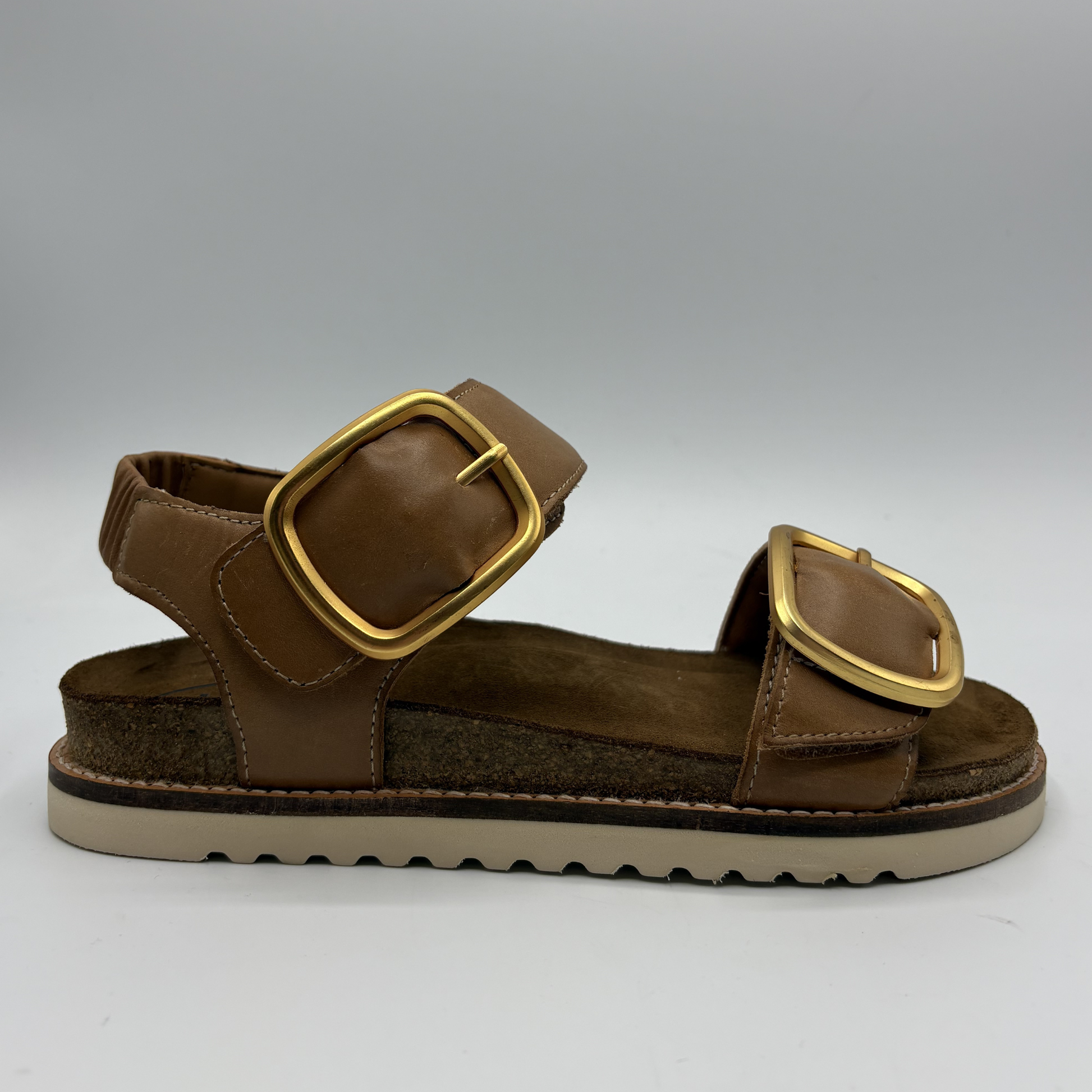 Brown sandal with gold buckles on a white background