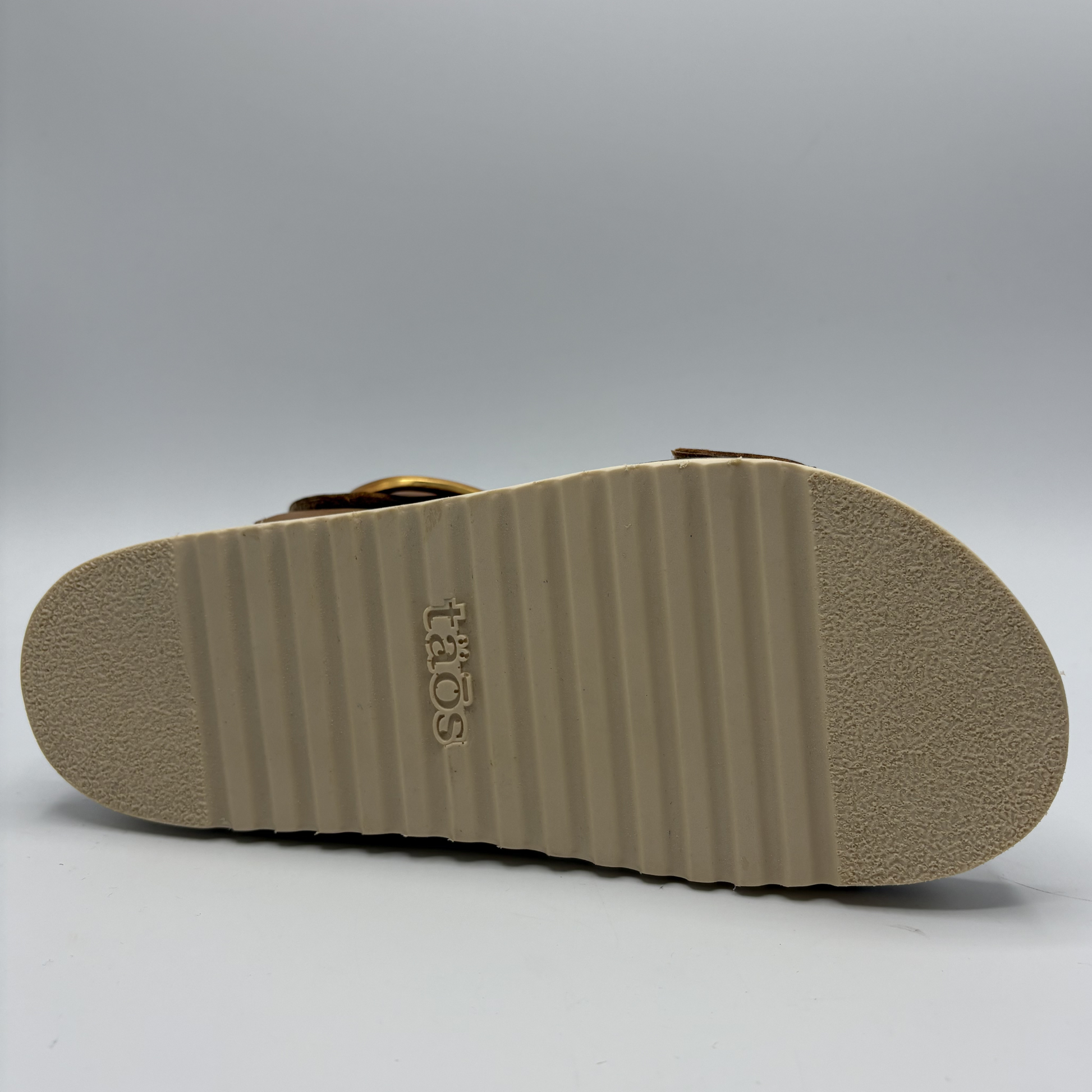 Tan sandal sole with 'Toms' branding on a gray background