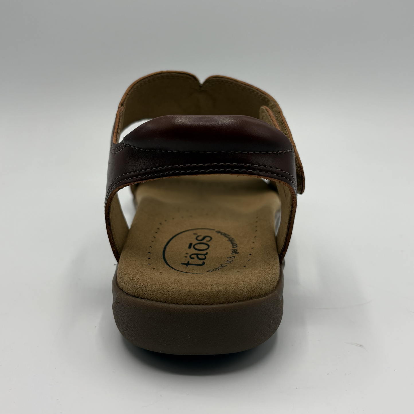 Brown sandal with 'taos' brand logo on a white background